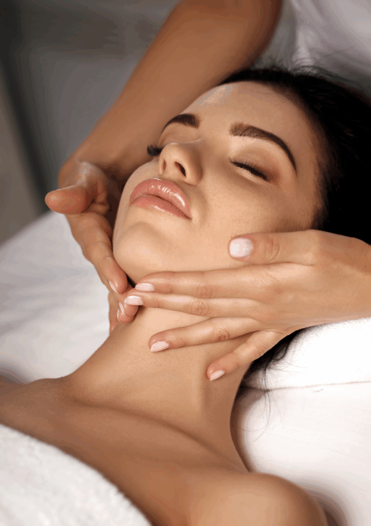 Woman receiving a facial massage on a facial table.